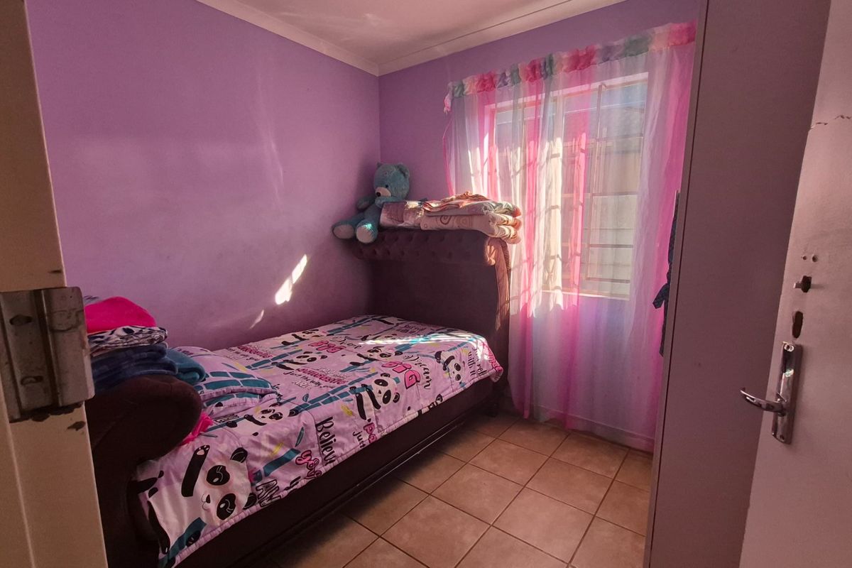 A standard bedroom featuring tiled flooring and a window, providing a functional space for a single bed.