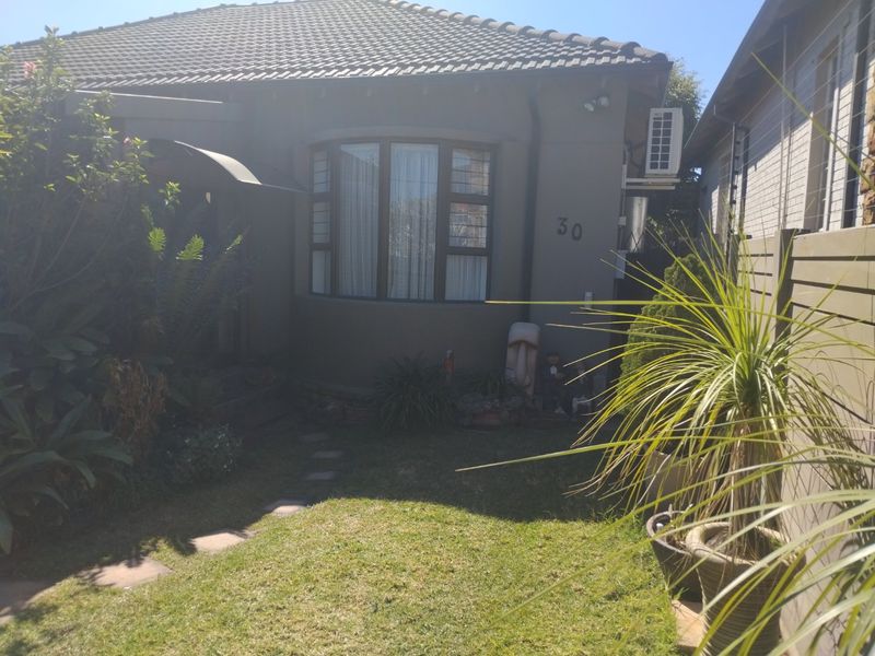Front view of the property featuring a tiled roof, bay window, and a small landscaped garden with a paved walkway.