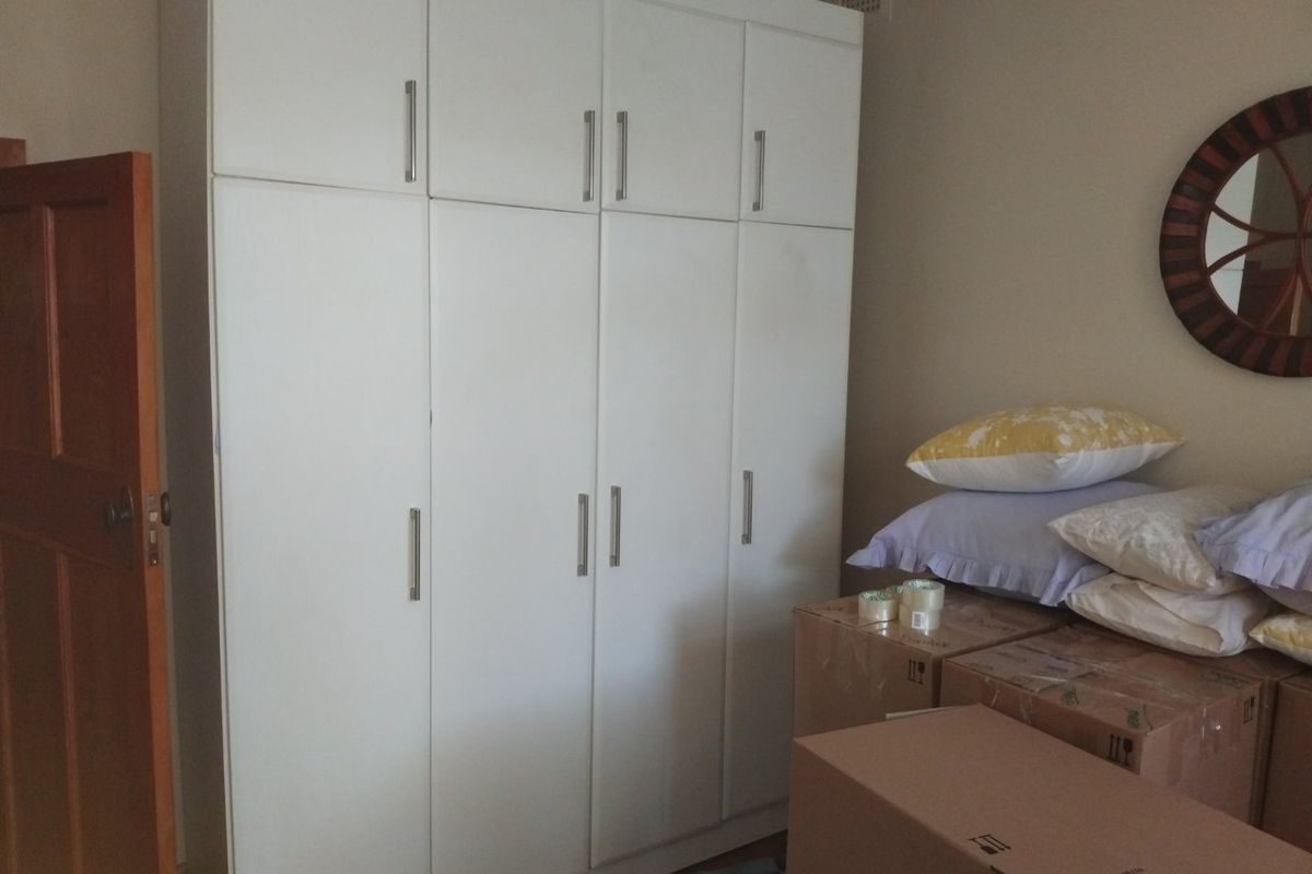 A bedroom featuring a large white built-in wardrobe with ample storage and a classic timber door.