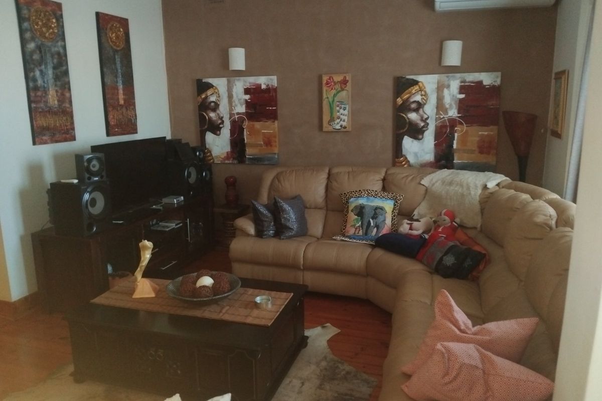 A comfortable living room featuring timber flooring, wall-mounted air conditioning, and ambient wall sconce lighting.