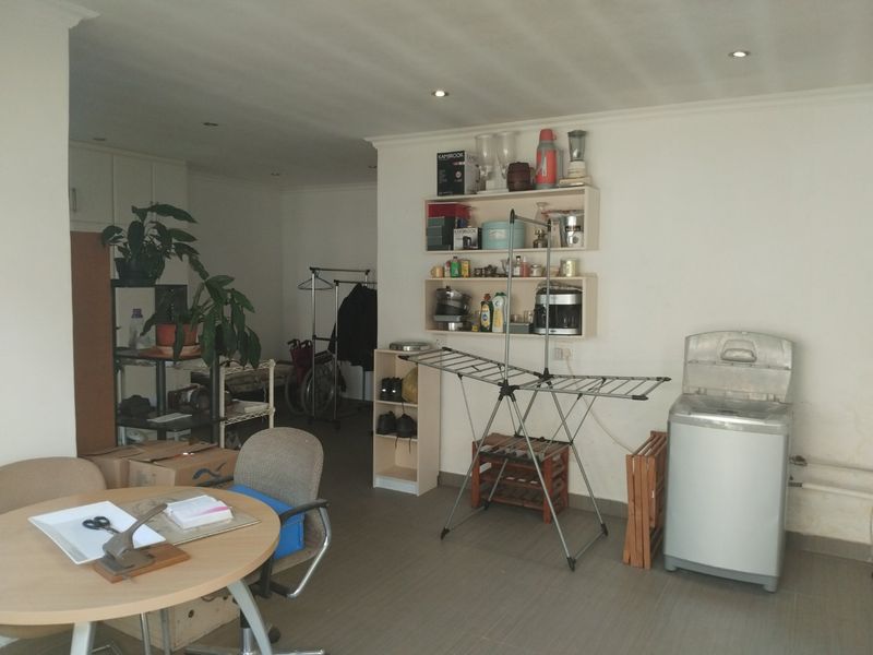 A functional laundry area featuring tiled flooring, recessed lighting, and wall-mounted storage shelving, currently utilized as a multi-purpose utility space.