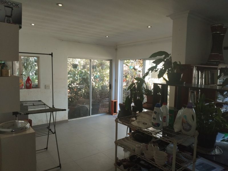 Open plan living area featuring tiled flooring, recessed downlights, and sliding glass doors providing access to the garden.