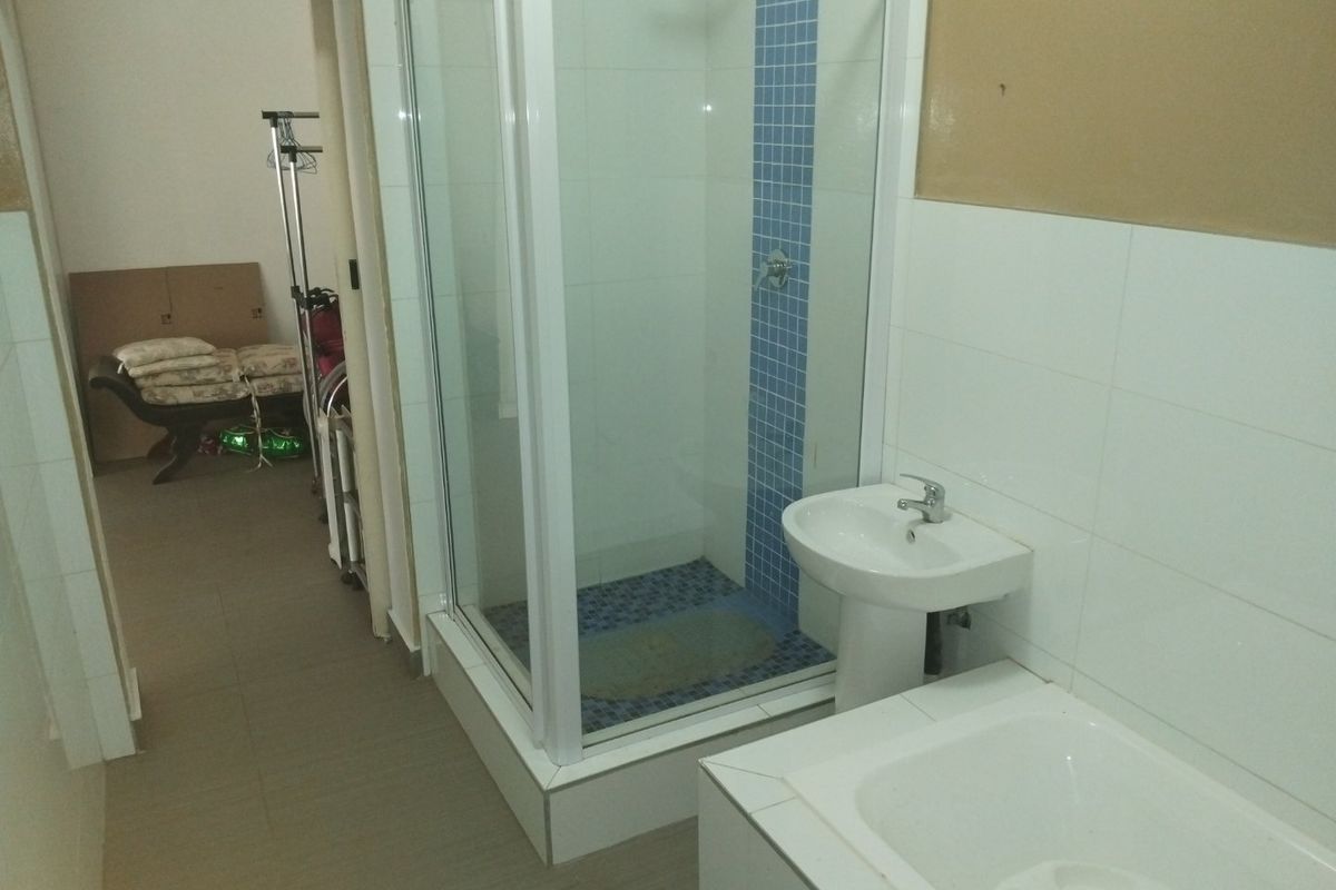A functional bathroom featuring a shower enclosure, pedestal basin, and built-in bathtub, requiring cosmetic updates to the wall finishes.