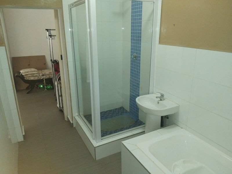 A functional bathroom featuring a shower enclosure, pedestal basin, and built-in bathtub, requiring cosmetic updates to the wall finishes.