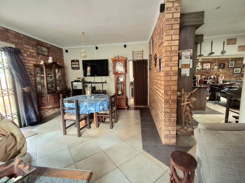 Spacious open-plan living and dining area featuring exposed brick walls, ceramic tile flooring, and a seamless transition into the adjacent kitchen space.