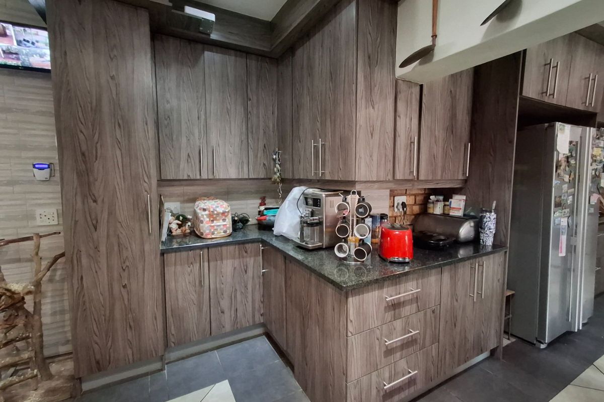 A functional kitchen featuring modern wood-grain cabinetry, granite countertops, and durable tiled flooring, offering ample storage and workspace.