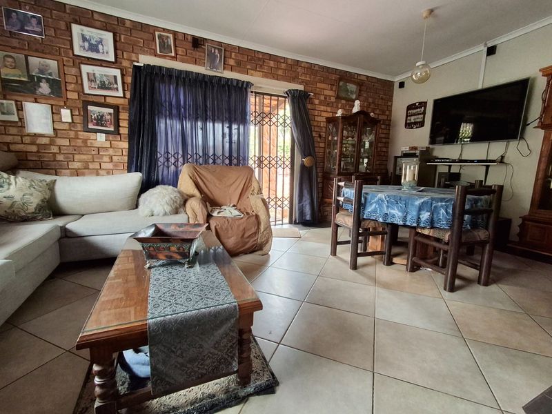 Open plan living and dining area featuring exposed brick walls, ceramic floor tiling, and direct access to the exterior through a security gate.