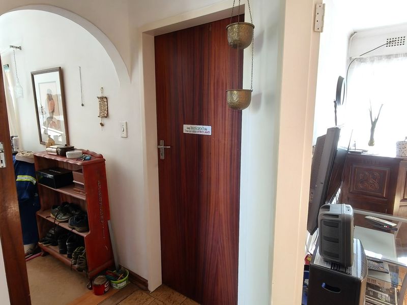 A functional hallway featuring a classic archway, a solid timber door, and cork flooring, providing access between living areas.
