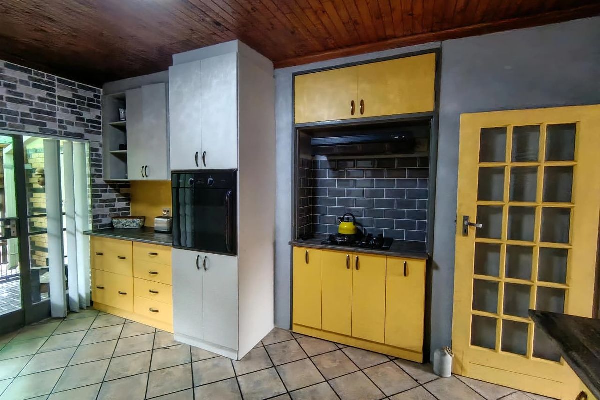 A kitchen featuring yellow cabinetry, built-in oven, gas hob with extractor fan, subway tile backsplash, and timber ceiling finishes.