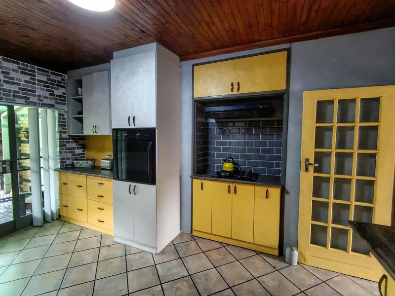 A kitchen featuring yellow cabinetry, built-in oven, gas hob with extractor fan, subway tile backsplash, and timber ceiling finishes.