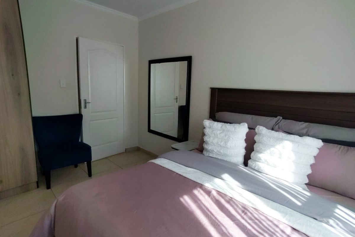 A well-maintained bedroom featuring tiled flooring, a built-in wardrobe, and coved ceiling details, providing a clean and functional living space.