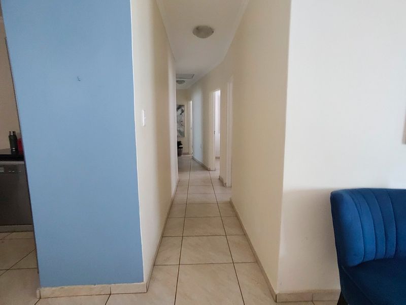 A functional hallway featuring neutral tiled flooring and access to multiple rooms, providing a clean and simple transition space within the home.