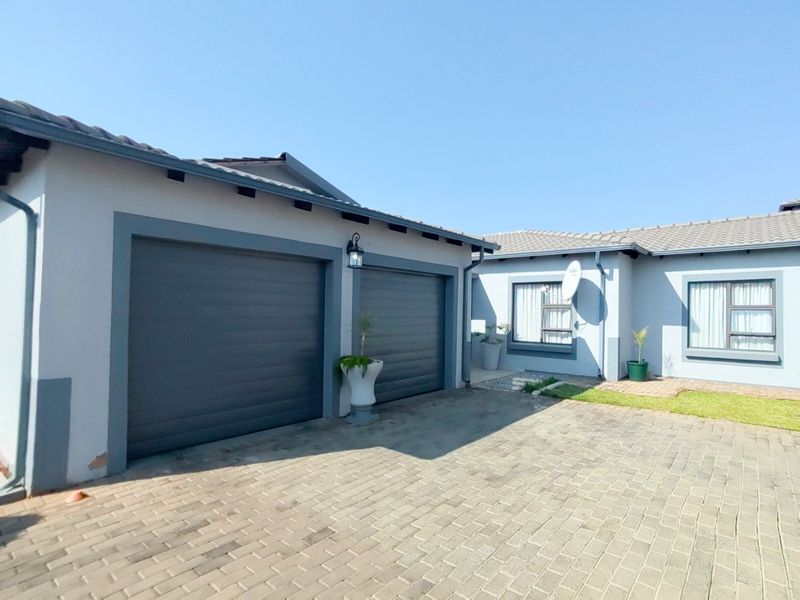 Front view of the property featuring a double garage, paved driveway, and well-maintained exterior walls with aluminium window frames.