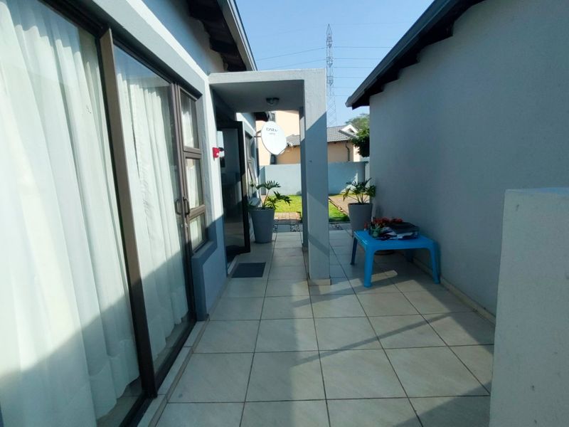 A covered outdoor patio area with tiled flooring, providing access to the home through sliding glass doors and leading towards the rear garden.