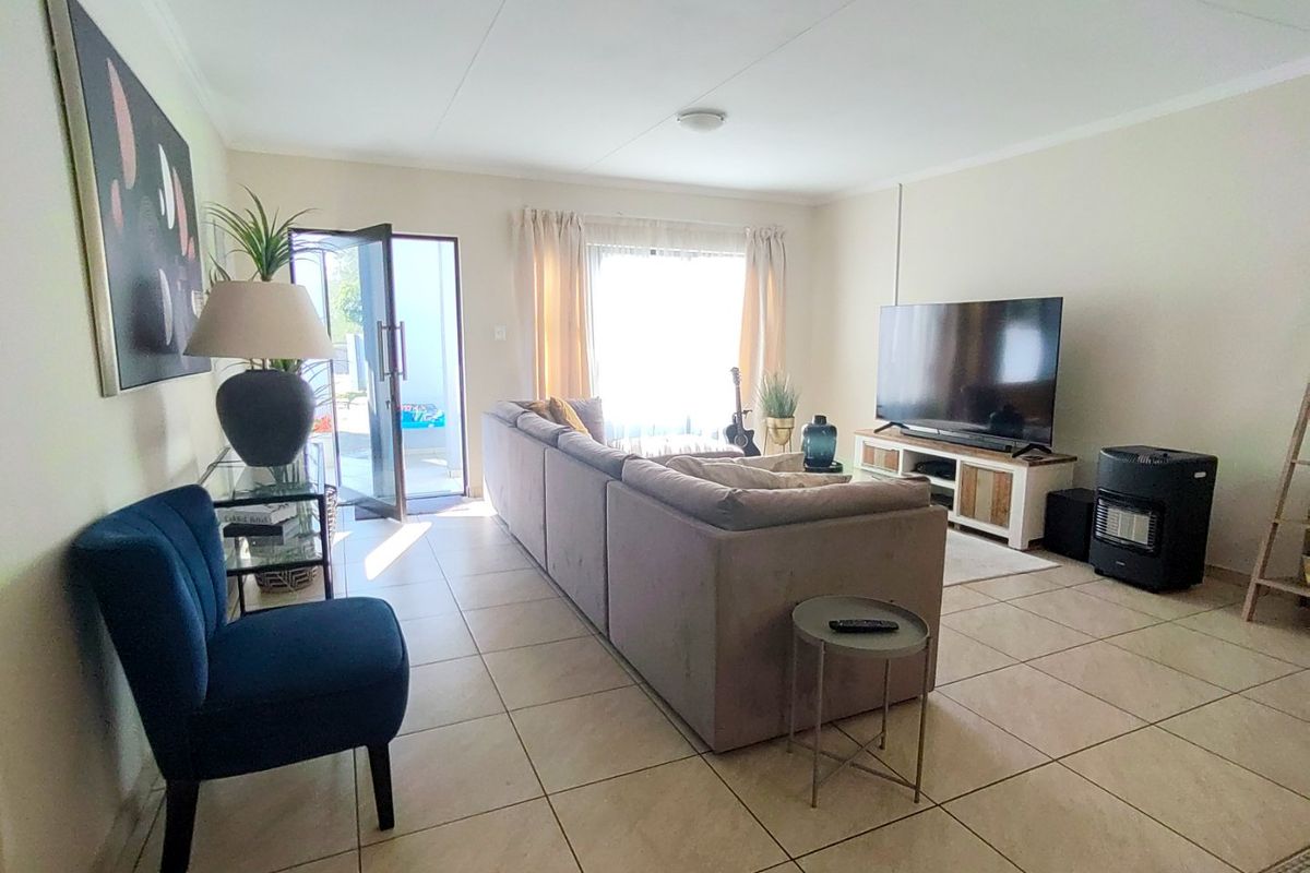 A bright living room featuring tiled flooring and a glass sliding door providing access to the outdoor area.