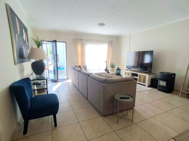 A bright living room featuring tiled flooring and a glass sliding door providing access to the outdoor area.