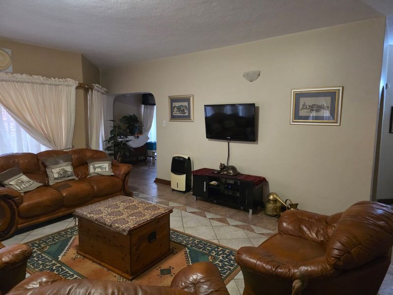 A spacious living room featuring tiled flooring and an arched entryway leading to adjacent living areas.
