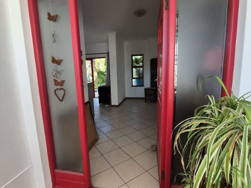 Entrance view featuring a distinctive red-painted timber door frame with frosted glass sidelights, leading into a tiled interior space.