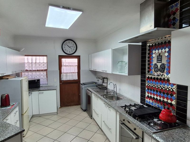 Functional kitchen featuring granite countertops, built-in oven, gas hob, extractor fan, and ample cabinetry with tiled flooring.