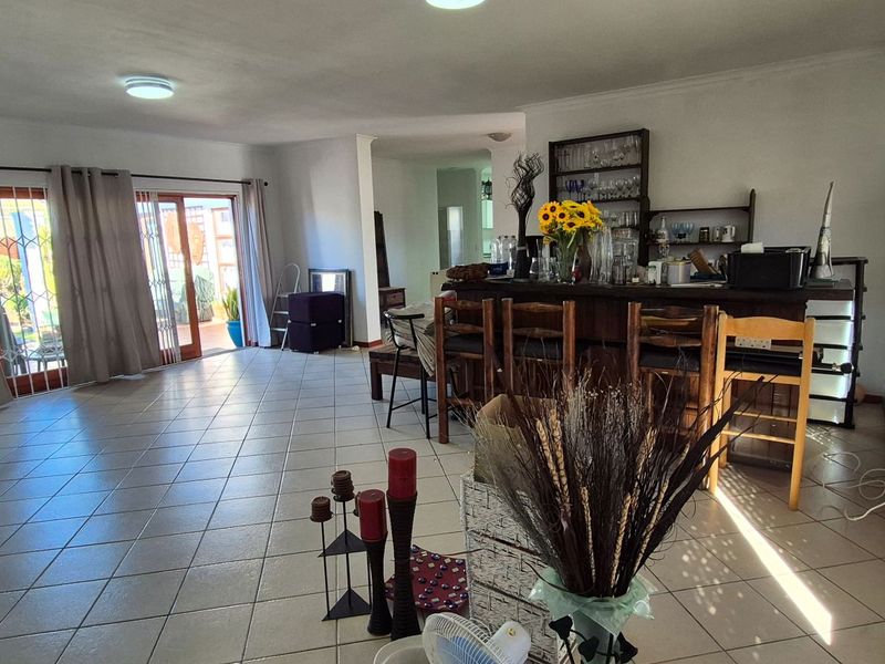 Spacious open-plan living area featuring tiled flooring, a built-in bar counter, and sliding glass doors providing access to the outdoor patio area.
