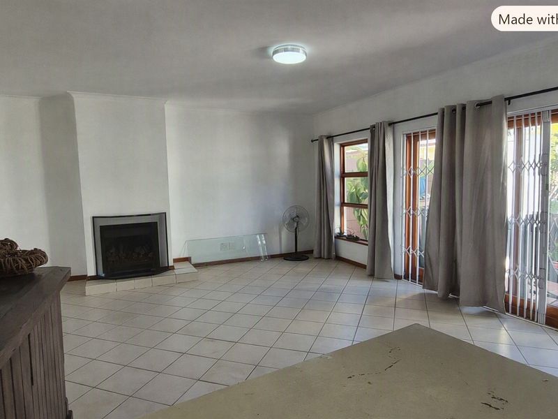 Spacious living room featuring tiled flooring, a built-in fireplace, and sliding glass doors providing access to the outdoor area.