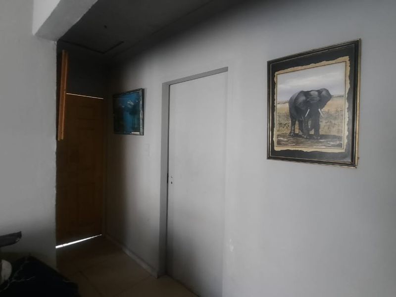 A simple interior hallway featuring tiled flooring and access to multiple rooms, requiring minor cosmetic updates to improve the overall finish.