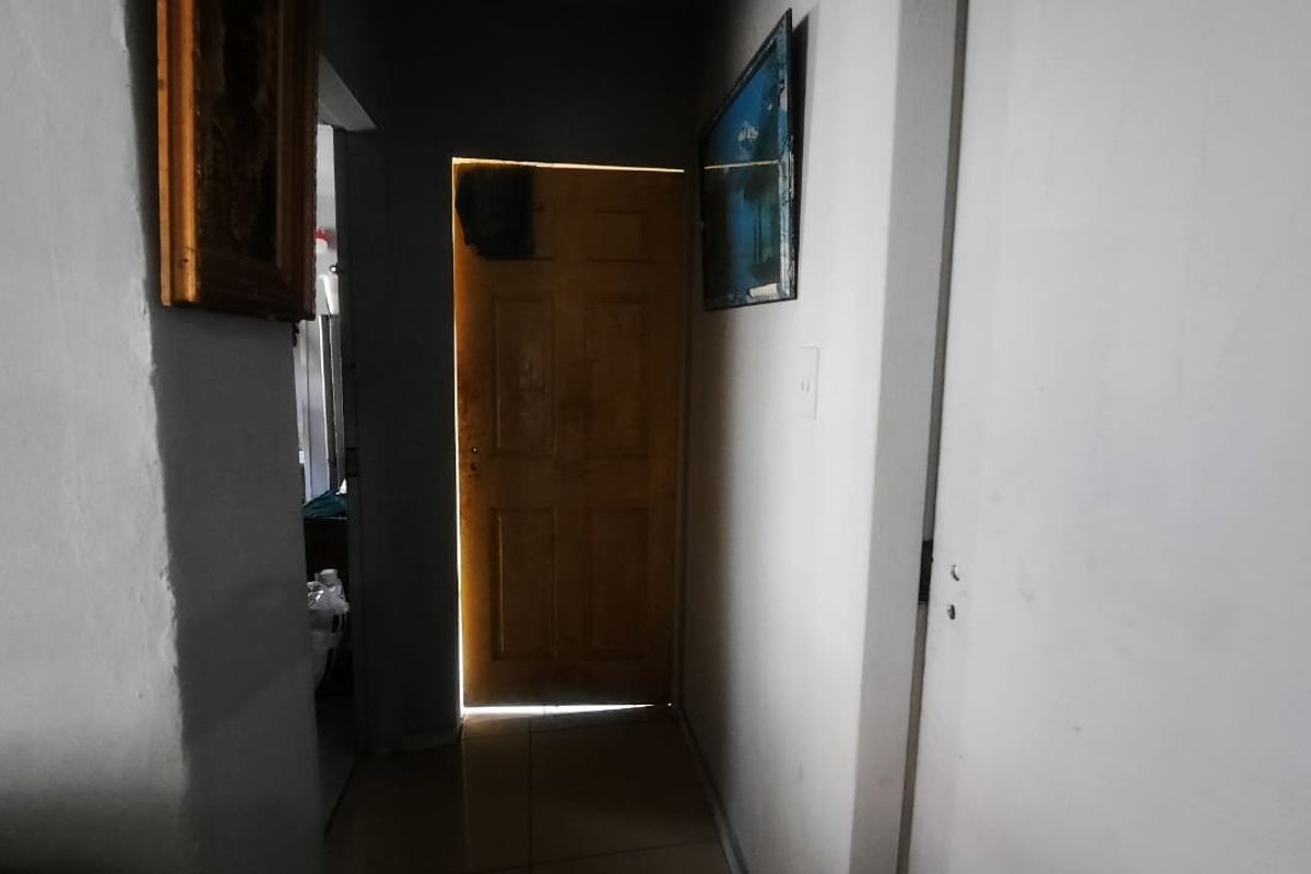 A narrow interior hallway featuring tiled flooring and a timber door, requiring cosmetic updates to improve the overall aesthetic.