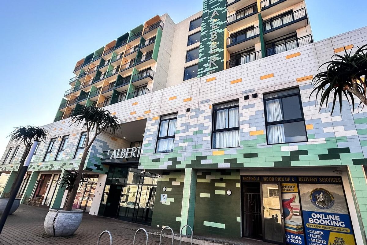 Exterior view of The Albert apartment building featuring a modern tiled facade, multiple balconies, and ground-floor commercial access.