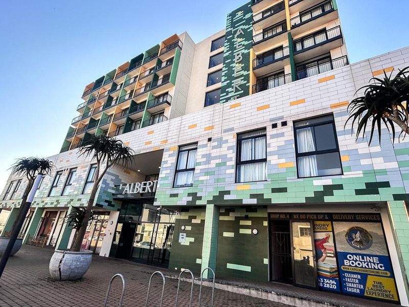 Exterior view of The Albert apartment building featuring a modern tiled facade, multiple balconies, and ground-floor commercial access.