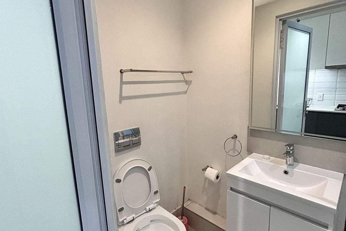 A modern, compact bathroom featuring a wall-mounted toilet, a sleek vanity with a washbasin, and a large wall mirror.