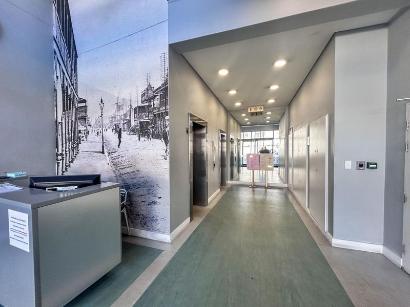 A modern apartment building entrance lobby featuring a reception desk, elevator access, and a decorative wall mural.