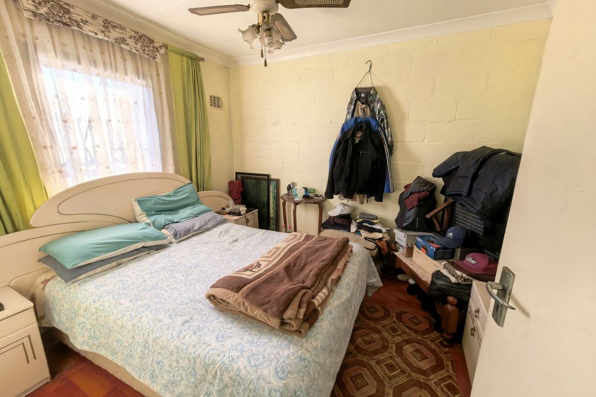 A bedroom featuring a ceiling fan and exposed blockwork walls, offering a functional space with potential for cosmetic updates.