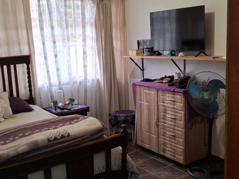 A functional bedroom featuring tiled flooring and natural light through window curtains, providing a comfortable and practical living space.