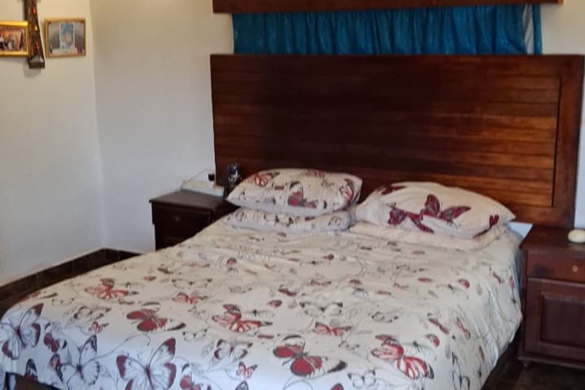 A bedroom featuring tiled flooring, a wall-mounted air conditioning unit, and a custom wooden headboard.