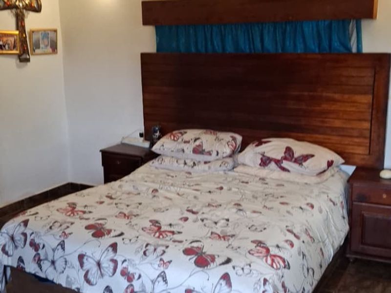A bedroom featuring tiled flooring, a wall-mounted air conditioning unit, and a custom wooden headboard.
