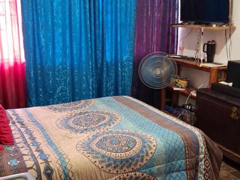 A bedroom featuring tiled flooring and window treatments, providing a functional space for rest.