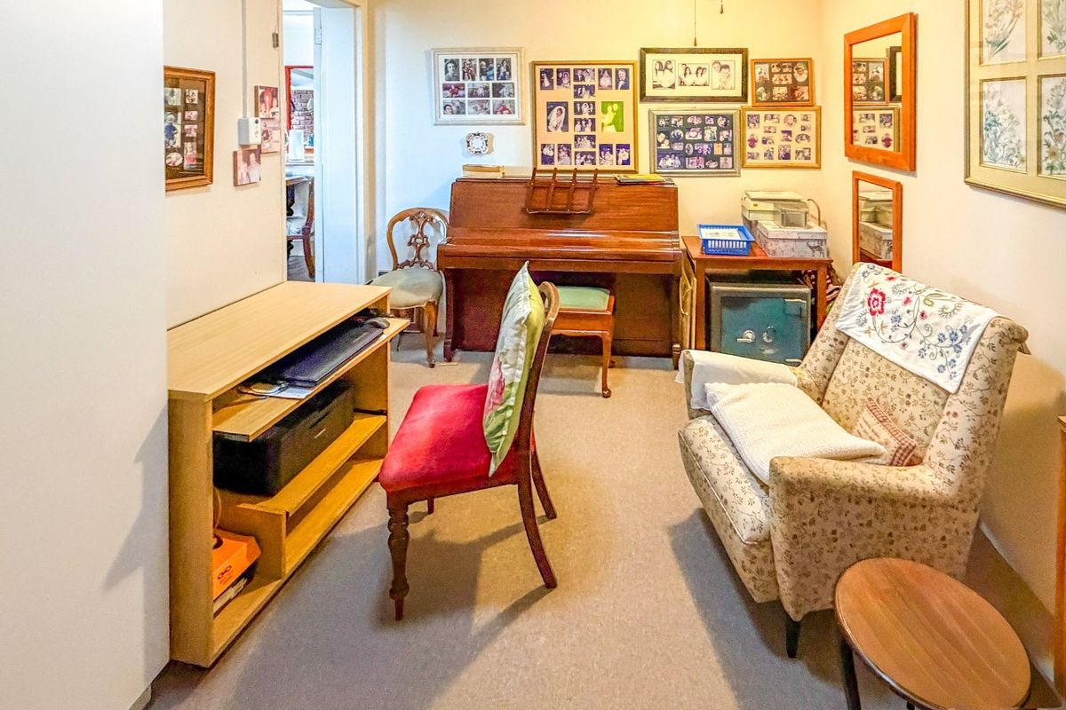 A carpeted living area with neutral walls, providing a versatile space that could serve as a lounge, study, or hobby room.