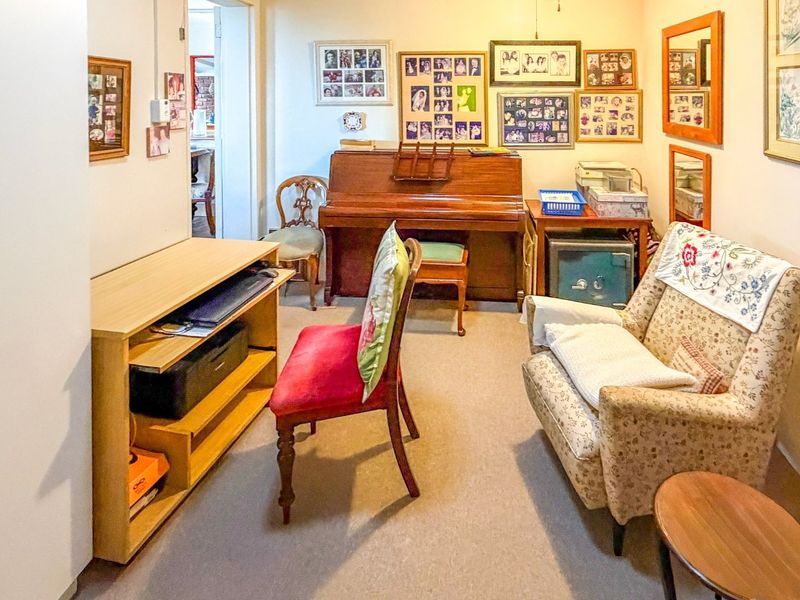 A carpeted living area with neutral walls, providing a versatile space that could serve as a lounge, study, or hobby room.