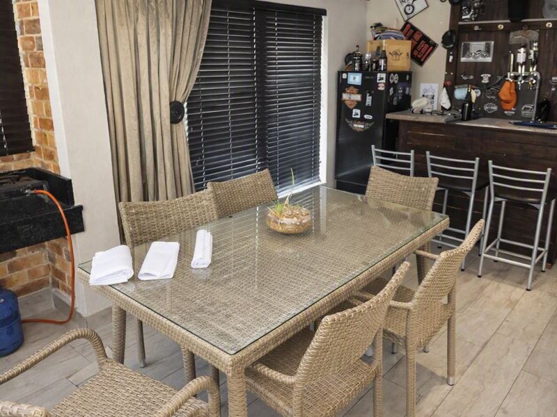 An indoor entertainment area featuring a built-in bar counter, a built-in braai, and tiled flooring, suitable for social gatherings.