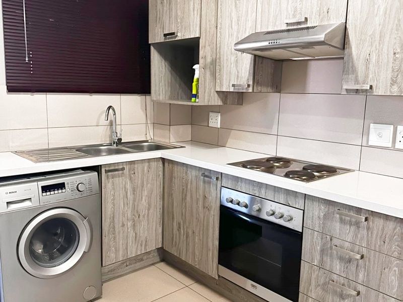 Modern kitchen featuring wood-look laminate cabinetry, integrated stainless steel appliances, tiled splashbacks, and a functional layout with ample counter space.