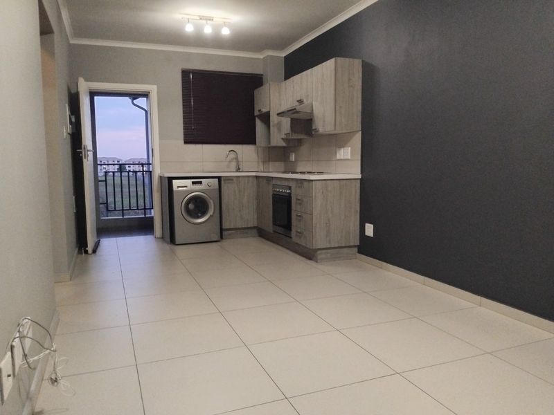 Open-plan kitchen and living area featuring modern wood-look cabinetry, tiled flooring, and direct access to a private balcony.