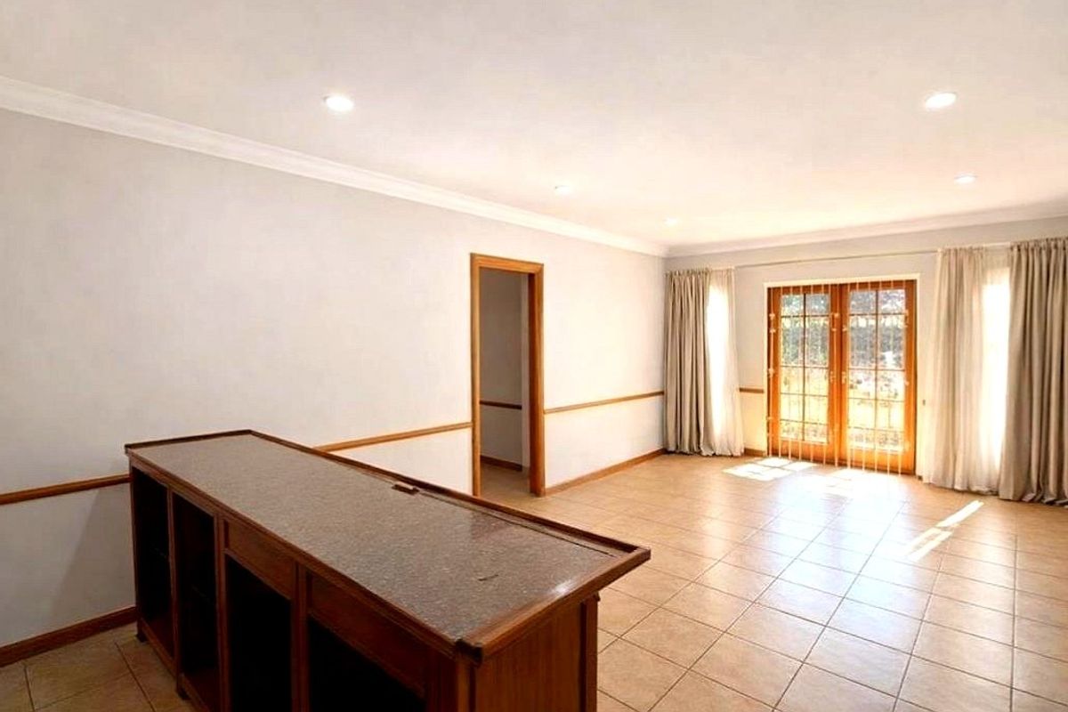 Spacious living area featuring tiled flooring, recessed downlights, a built-in wooden bar counter, and glass french doors leading to the exterior.