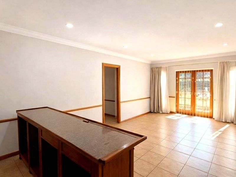 Spacious living area featuring tiled flooring, recessed downlights, a built-in wooden bar counter, and glass french doors leading to the exterior.