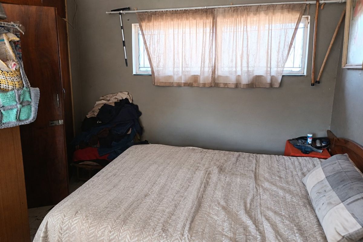 A bedroom featuring a built-in wardrobe and a window with security bars, requiring cosmetic updates to improve the overall aesthetic.