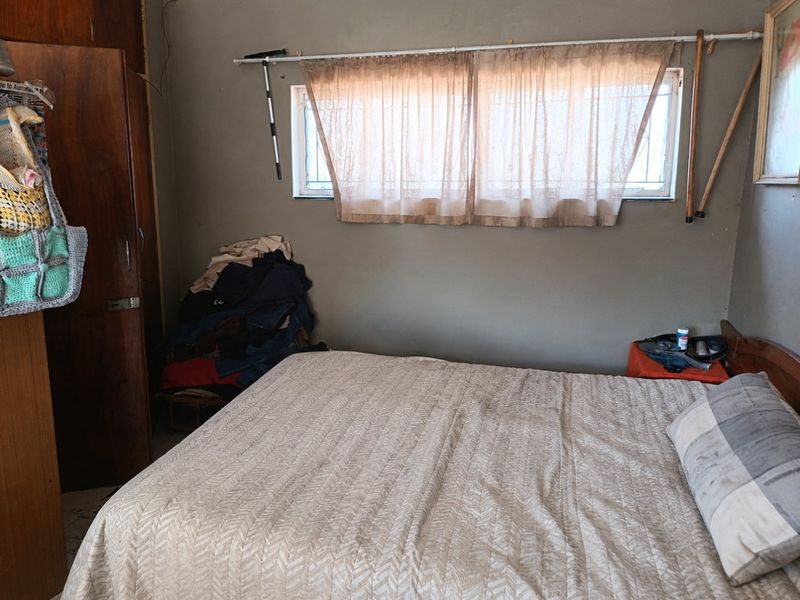 A bedroom featuring a built-in wardrobe and a window with security bars, requiring cosmetic updates to improve the overall aesthetic.