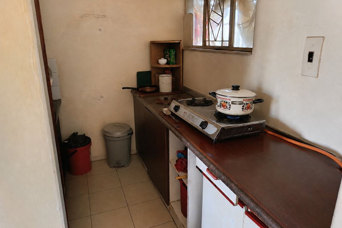 Compact kitchen area featuring basic base cabinetry, laminate countertops, tiled flooring, and a gas hob setup.