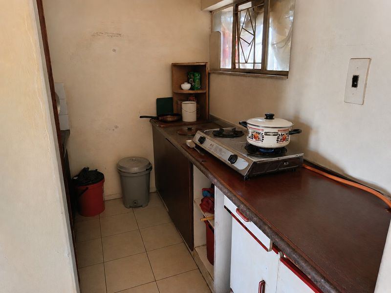 Compact kitchen area featuring basic base cabinetry, laminate countertops, tiled flooring, and a gas hob setup.