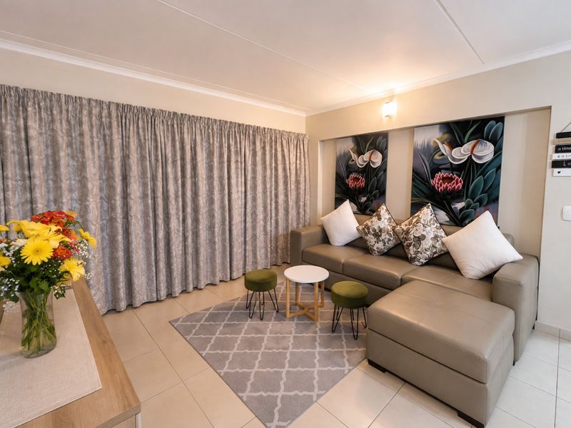 A well-maintained living room featuring neutral tiled flooring and a wall-mounted light fixture, creating a comfortable and inviting space.