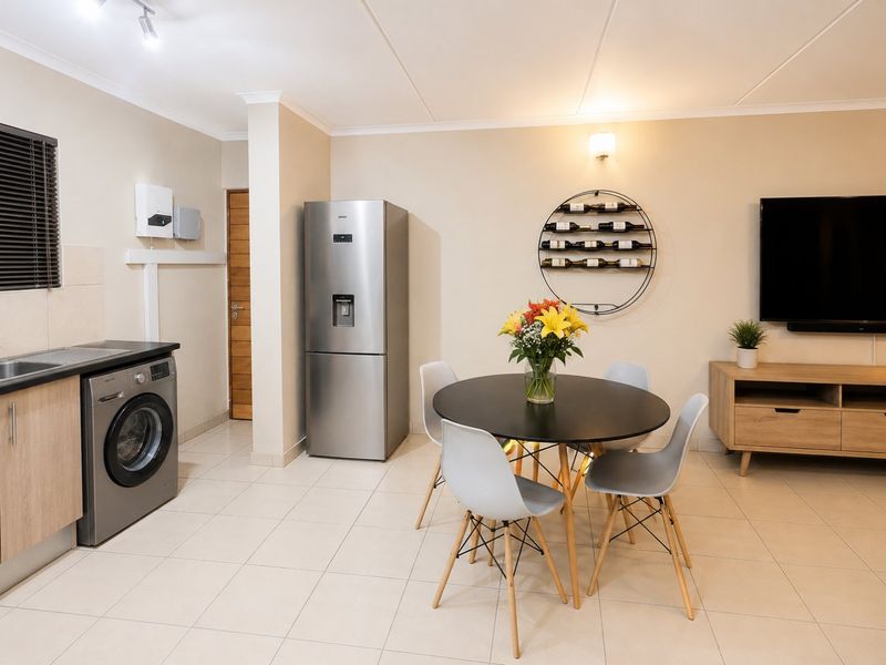 An open-plan living and kitchen area featuring tiled flooring, neutral walls, and integrated laundry facilities, creating a functional and cohesive living space.