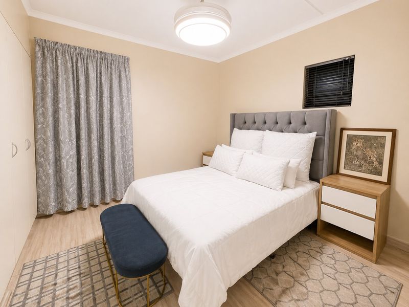 A well-maintained bedroom featuring laminate flooring, built-in cupboards, and a neutral color palette, providing a comfortable and functional living space.